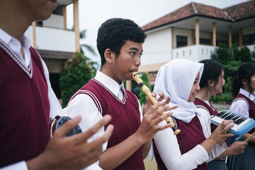 Asian Multiethnic High School Students Playing Music Instruments Together At School Field