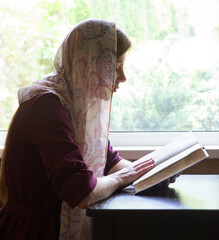 Girl reading a book by the window