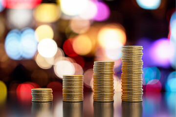 Abstract growing stacked coins on blurry dark bokeh background with mock up place. Financial growth...
