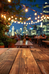 A wooden bar top in the foreground with a blurred background of an urban rooftop bar. The background includes stylish seating, plants, string lights, a panoramic city view.