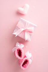 Pink baby shower gift box with ribbon, crocheted booties, and heart on pink vertical background....