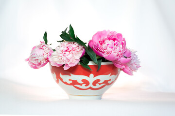 Kazakh traditional bowl — piala with national ornament filled with blooming peonies. Pefrect photo for Nauryz greetings
