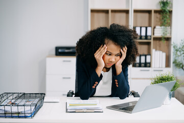 Frustrated young businesswoman working on a laptop computer sitting at his working place