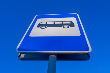 Road sign bus stop against a background of a bright blue sky.