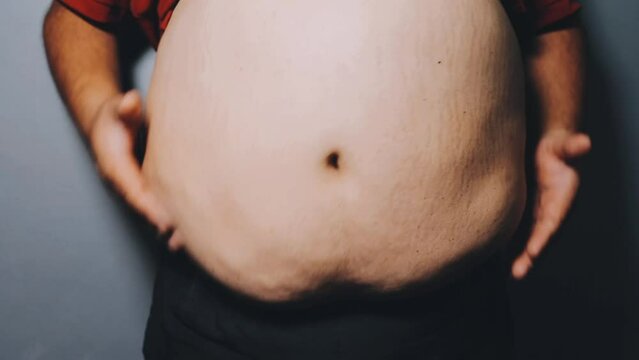 Man pointing own unhealthy big belly with visceral or subcutaneous fats. Pose health risk.