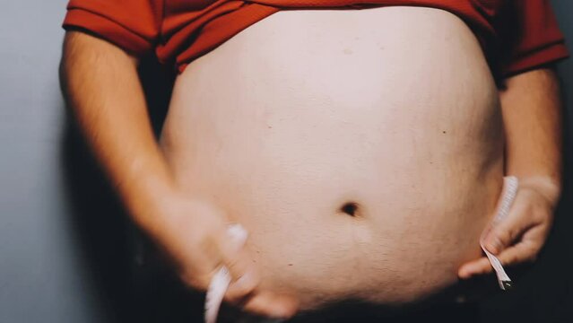 Man pointing own unhealthy big belly with visceral or subcutaneous fats. Pose health risk.