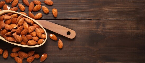 Almonds in wooden bowl and wooden spoon with brown napkin on wooden table top view for copy space