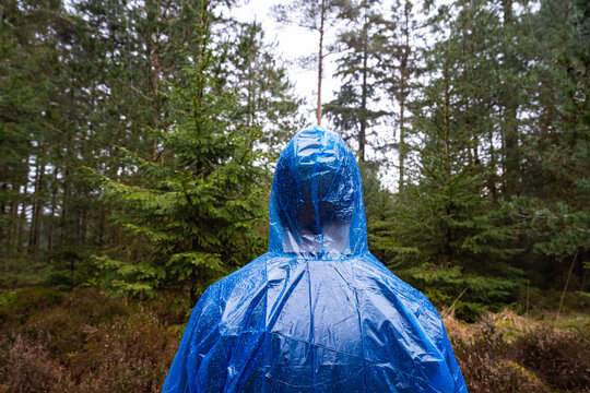 Man in blue plastic poncho walking in a forest