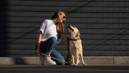 A blind woman walks her guide dog on the street. Girl hugging a labrador. 
