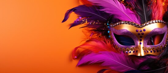 A vibrant flat lay featuring a close up of a Mardi Gras or Carnival mask on a bright orange and violet background The image offers ample copy space