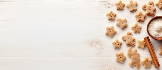 A composition featuring a copy space image with cookie cutters a whisker and a rolling pin on a white textured wooden surface as seen from above