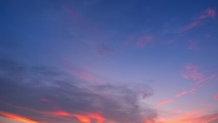A vivid sunset with a sky that transitions from deep blue at the top to soft pink and orange near the horizon. Wisps of clouds reflect the sunset colors, creating a dramatic and beautiful scene.
