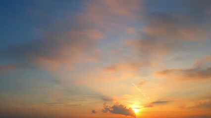 A stunning sunset with the sun partially visible near the horizon, casting a warm golden glow. The...