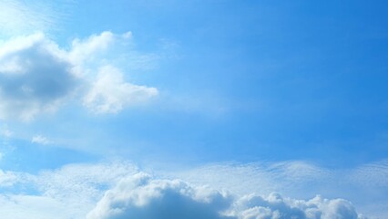 A bright blue sky dotted with various types of clouds. Some clouds are fluffy and dense, while...