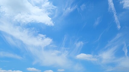 A beautiful blue sky with delicate, wispy clouds. The light, airy clouds are spread out, creating a...
