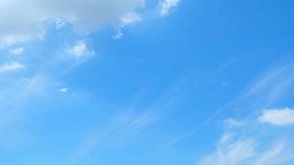 A bright blue sky with a few scattered clouds. The clouds vary in shape, with some appearing fluffy...
