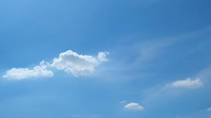 A blue sky with a few scattered, fluffy white clouds. The clouds add a touch of softness to the...