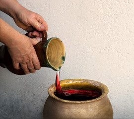 A hand holds a clay jar and pours water