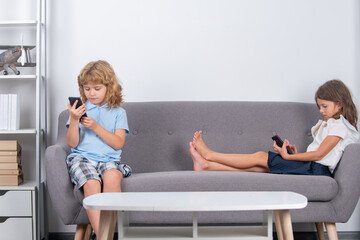 Two children alone with phone at home. Gadget addiction. Mobile addict concept. Parental control, social media addiction. Kids playing on smartphone.