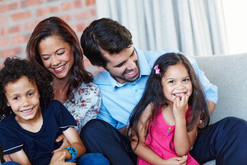 Portrait, happy and family in home living room for care, support and interracial people bonding together to relax. Face, mother and father playing with kids on sofa for love, connection and laughing