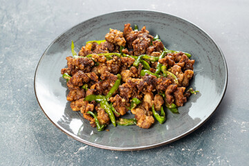 Stir Fried Green Chilli Chicken Dry served in plate isolated on grey background closeup side view...