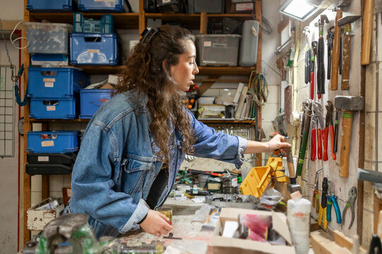 Woodworker choosing tools from pegboard at workshop