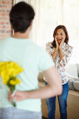 Couple, house and flowers with woman surprised for anniversary with expression in living room....
