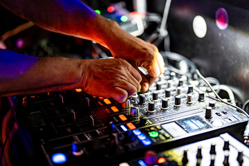 DJ controlling sound mixer at nightclub