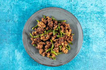 Stir Fried Green Chilli Chicken Dry served in plate isolated on blue background closeup top view of...