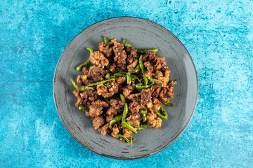 Stir Fried Green Chilli Chicken Dry served in plate isolated on blue background closeup top view of bangladeshi food