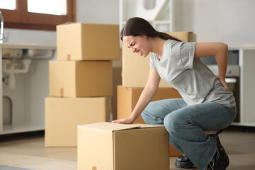 Woman moving house suffering back ache lifting box