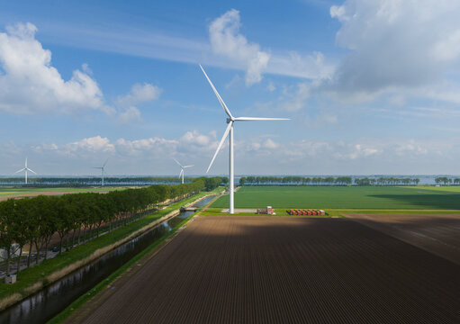 Wind turbines on fields under cloudy sky