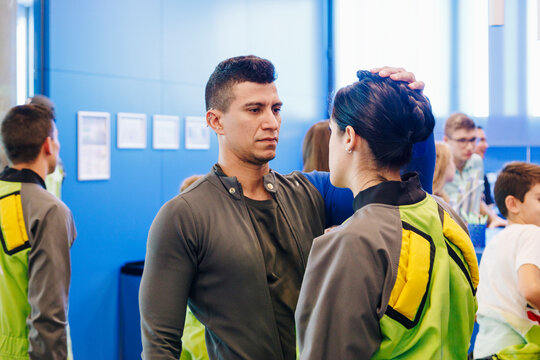 Serious instructor tying hair of woman in changing room at indoor skydiving center