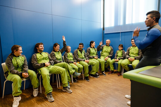 Instructor discussing with participants in sportswear at indoor skydiving center