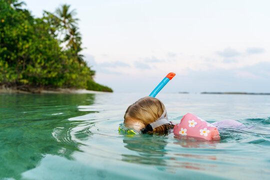 Girl snorkeling with water wings in sea at sunset