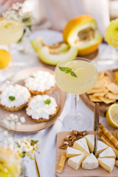 Fresh lemonade in glass with cheese and sweets on table