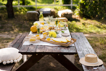 Wooden picnic table decorated with various food in garden