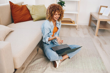 Smiling woman typing on laptop in a cozy living room, enjoying the freedom of online freelance work