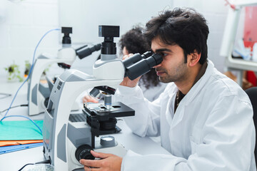 Scientist analyzing sample with microscope in laboratory
