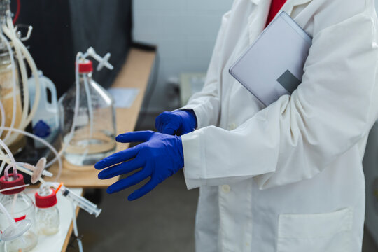 Scientist wearing glove standing by bioreactor in laboratory