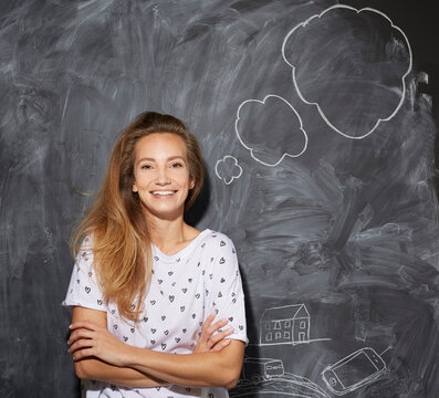 Smiling woman with arms crossed in front of thought bubble on chalkboard