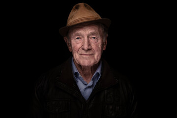 Senior man wearing hat against black background
