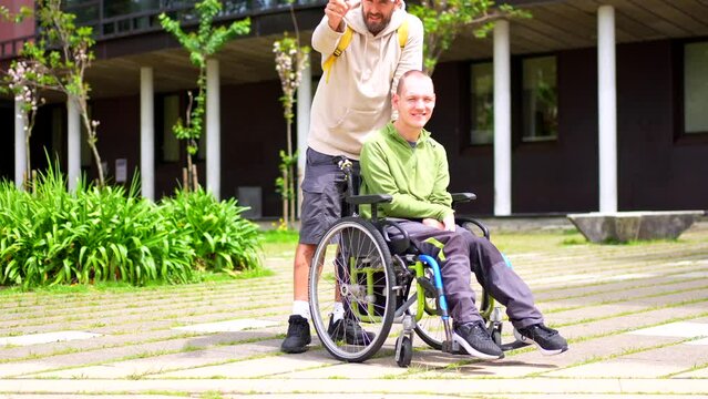 Full length photo of a caucasian adult man with special needs and friend walking along the university campus