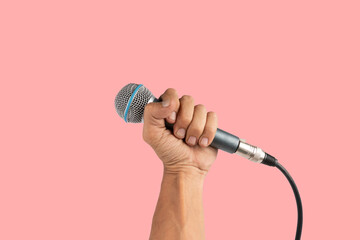 Black male hand holding a microphone isolated on pink background