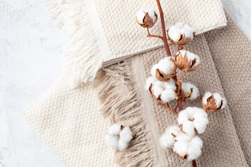 Branch of cotton flowers on soft bath terry towel background top view. Eco and organic bathroom...