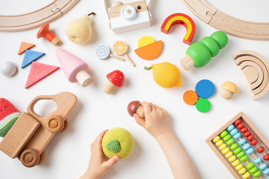 Toddler children activity for motor and sensory development. Baby hands with colorful wooden toys on table from above.
