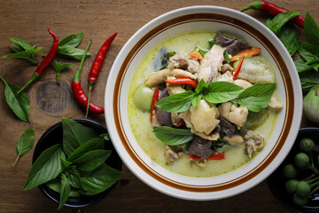 Thai food. Chicken green curry in a white bowl placed on a wooden table. Popular authentic Thai food concept.