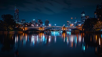 A beautifully illuminated bridge spanning a calm river at night, with the city skyline reflecting on the water.