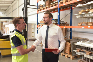 Worker and Manager in a warehouse in the logistics sector - handshake in the morning to start working in a new job