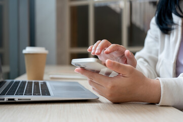 A close-up image of a woman working remotely at a coffee shop, using her smartphone.